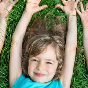 three young girls reaching for the air as they lay on the grass