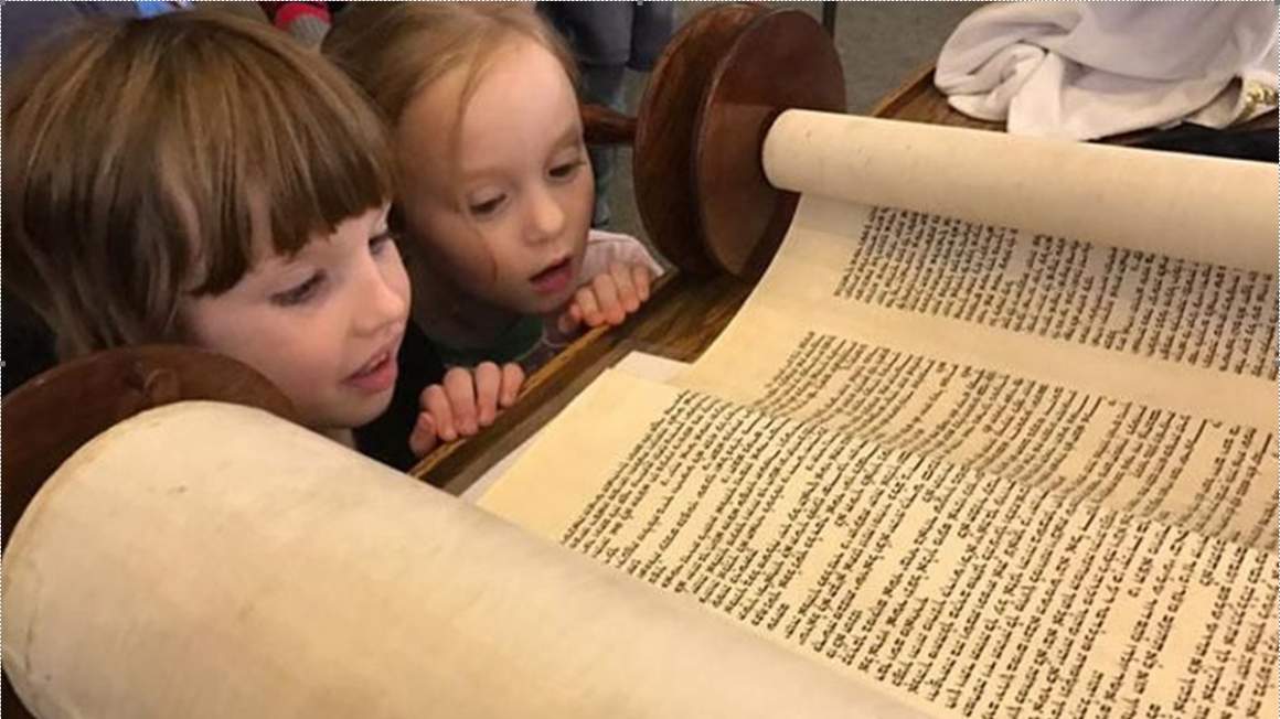 two little girls looking at the torah